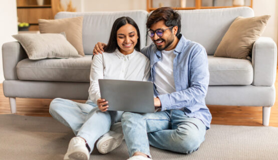 Man and Woman Sitting on Floor Looking at Laptop